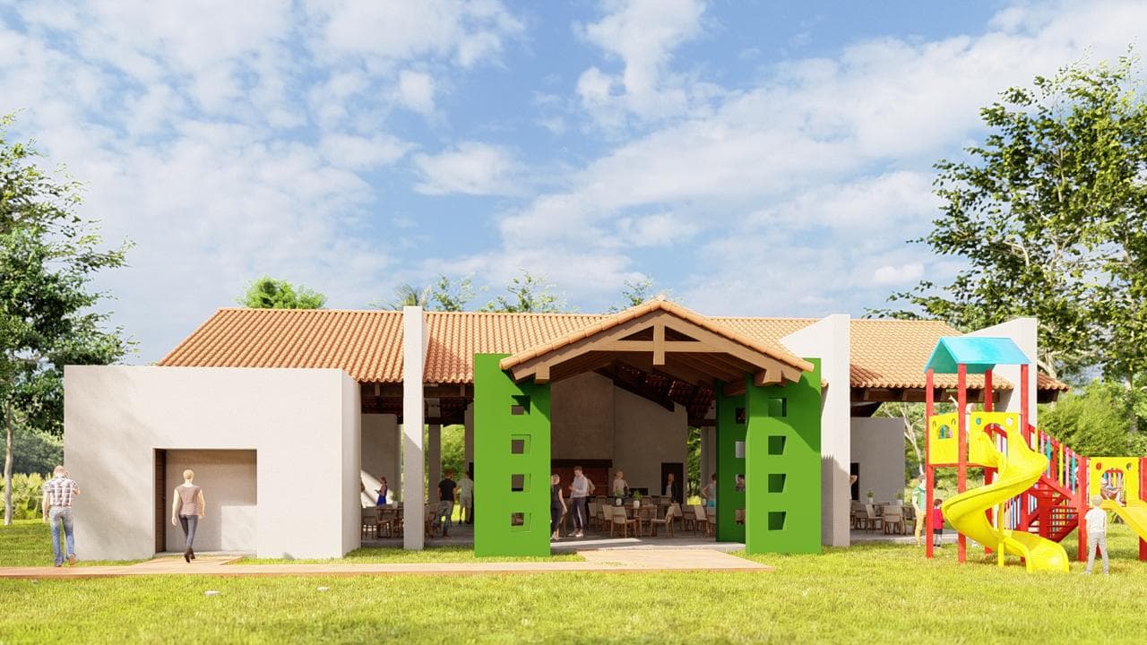 Render del club house visto de frente, con su techo de teja, el ingreso entre columnas verdes y el parque infantil al costado.